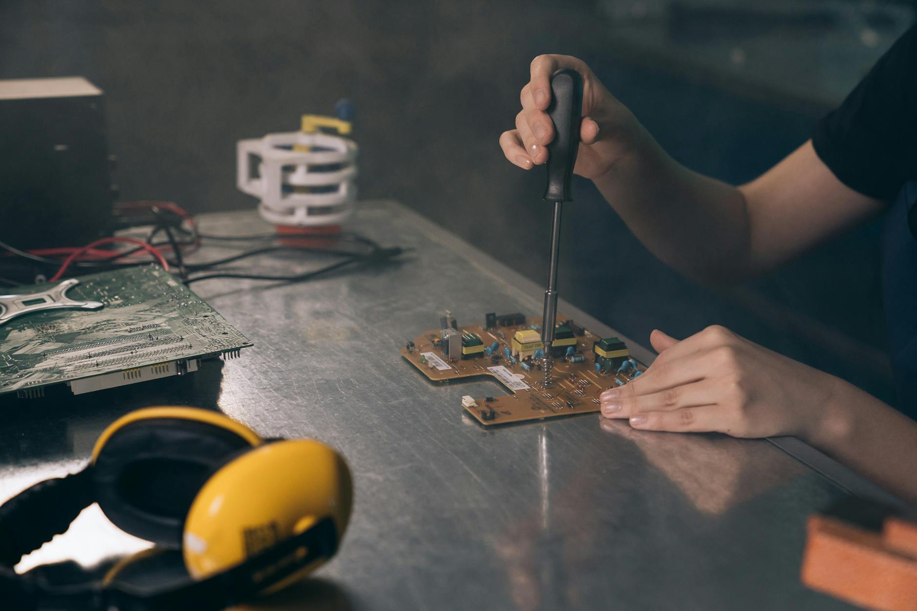 Personne qui soude des composants electroniques sur une plaque Arduino